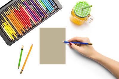 Midsection of human hand holding pencils against white background