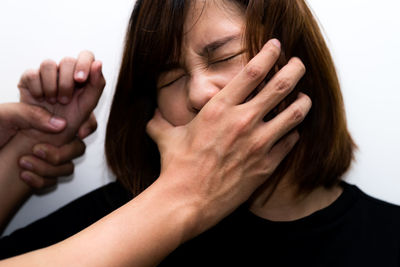 Close-up portrait of a woman with hand on white background