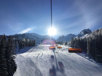 Ski lift over snow covered mountains against sky