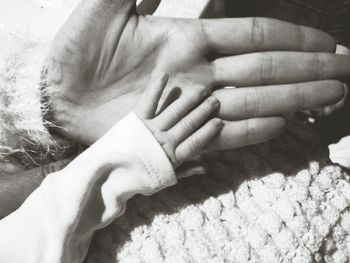 Cropped hands of mother and child on bed