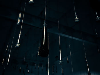 Low angle view of illuminated light bulb hanging on ceiling in building