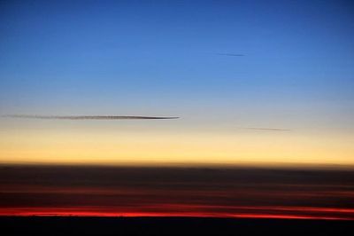 Silhouette of airplane flying in sky at sunset