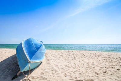 Deck chairs on beach against blue sky