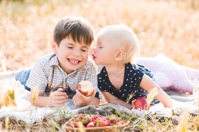 Cute sister kissing brother while lying on grass