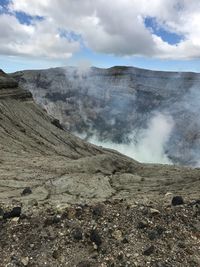 Smoke emitting from volcanic landscape against sky