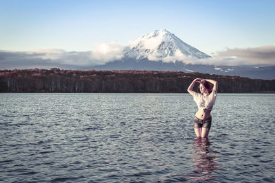 Woman standing in river against snowcapped mountain