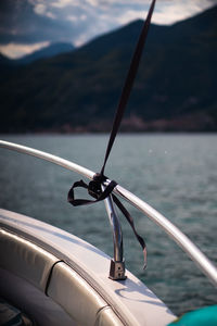 Rope tied to the rail of a boat with water in the background