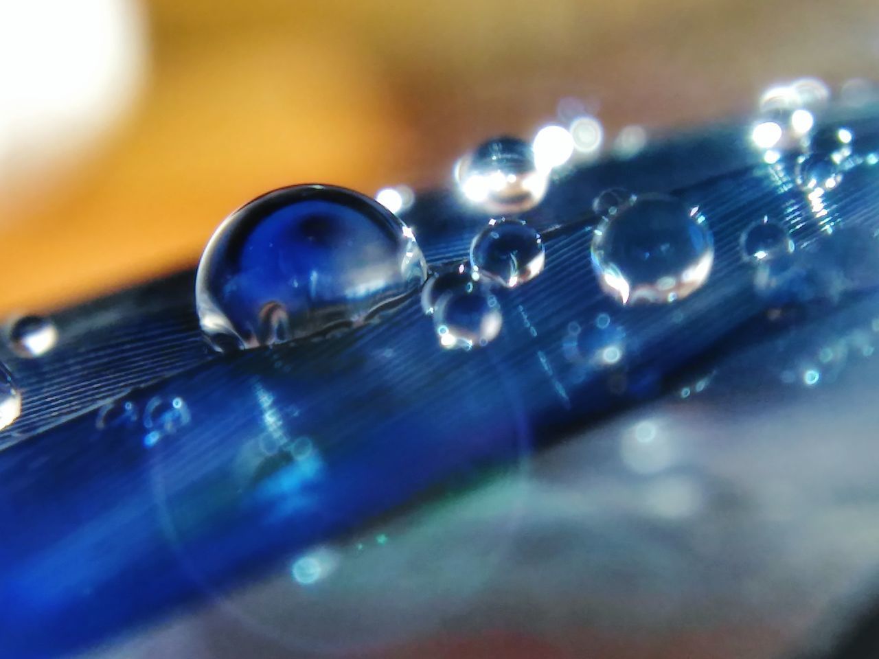 CLOSE-UP OF WATER DROPS ON GLASS OF LIGHT