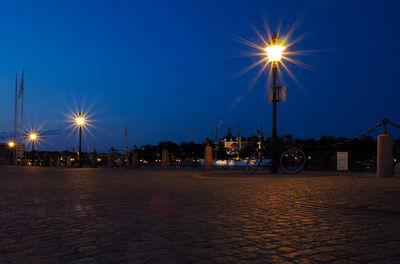 Illuminated street lights against sky at night