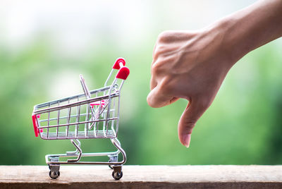 Close-up of woman gesturing by figurine shopping cart 