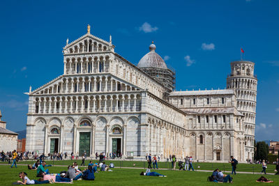 Group of people in front of historic building against blue sky