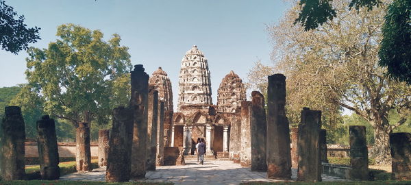 Rear view of people walking in temple against sky
