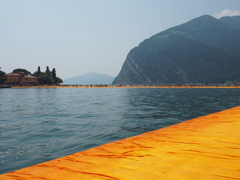 Scenic view of sea by mountains against sky