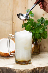 Cropped hand preparing drink at tree stump