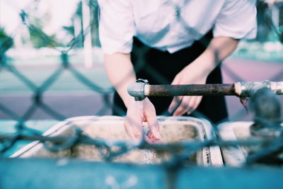 Midsection of woman washing hands in sink at park