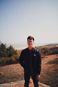 Portrait of young man standing on land against sky