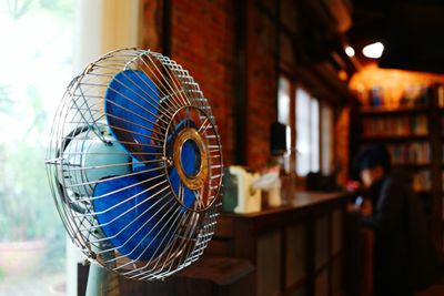 Close-up of electric fan against window at restaurant