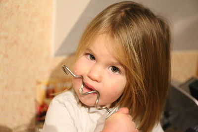 Portrait of cute girl holding spiral metal tool at home