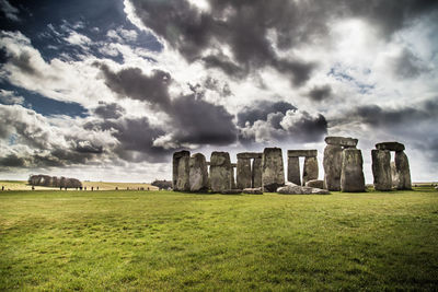 Built structure in field against cloudy sky