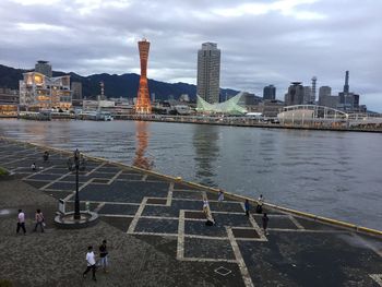 View of buildings by river against cloudy sky