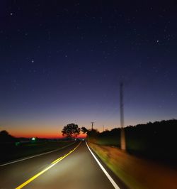 Road amidst trees against sky at night