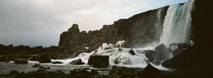 Panoramic view of waterfall by sea against sky