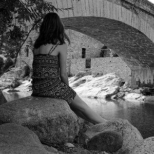 Young woman sitting on rock at shore