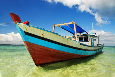 Boat moored on sea shore against sky