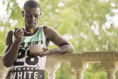 Portrait of young man standing against railing