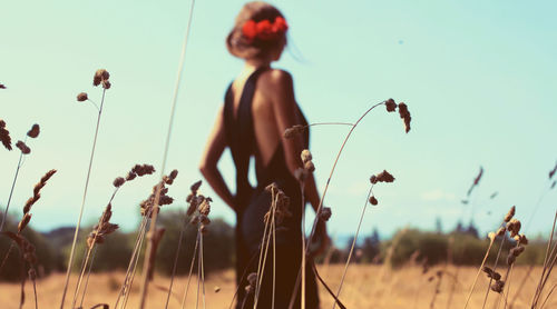 Low angle view of young woman standing in field during sunny day