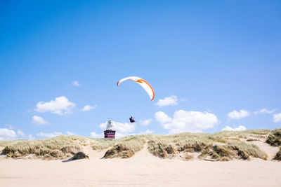 Low angle view of person paragliding against clear blue sky