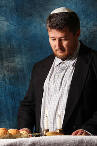 Man looking at burning candles on table against wall