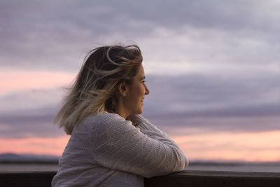 Woman looking at sea against sky during sunset