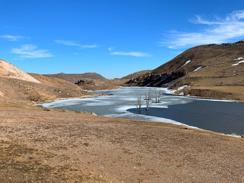 Scenic view of land and mountains against blue sky