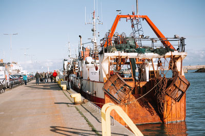 Fishing boats moored at harbor against clear sky