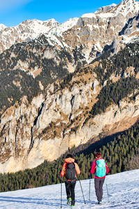 Rear view of people walking on rocks against mountain