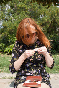 Woman rolling marijuana joint while sitting outdoors