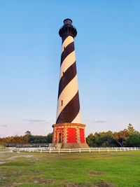 Lighthouse on field against clear blue sky