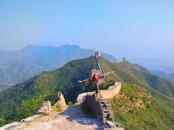 Man standing on retaining wall at great wall of china against sky