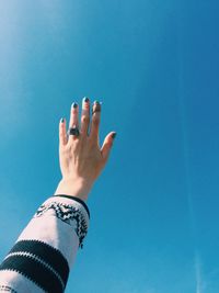 Cropped hand of woman gesturing against clear blue sky