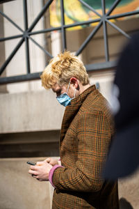 Woman holding mobile phone while standing on camera
