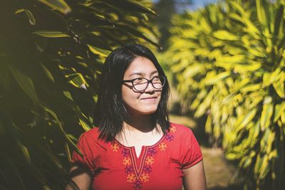 Close-up of smiling young woman looking away by plants