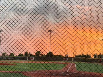 Chainlink fence against sky during sunset