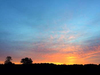 Low angle view of silhouette trees against dramatic sky