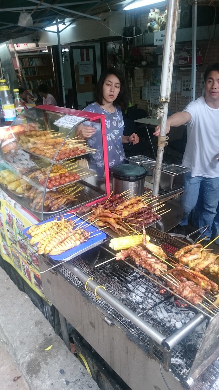 real people, food, food and drink, market, for sale, retail, market stall, looking at camera, standing, freshness, night, one person, large group of objects, indoors, portrait, illuminated, healthy eating, occupation, working, men, young adult, people