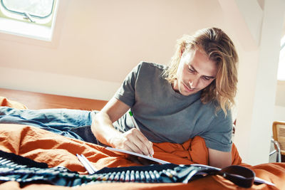 Young woman sitting on bed at home