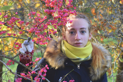 Close-up portrait of young woman with flowers and leaves
