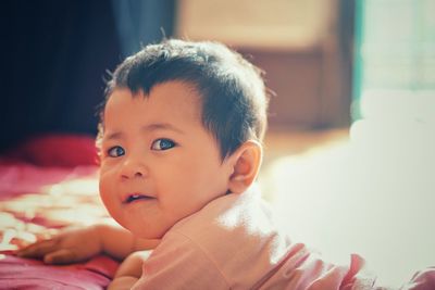 Close-up portrait of cute baby girl on bed at home