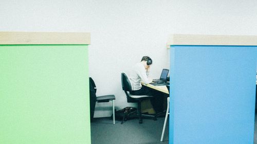 Man working on table against wall