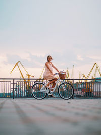 Woman on bicycle against sky